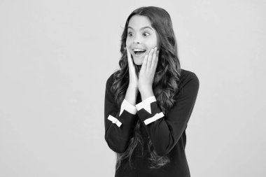 Heyecanlı bir yüz. Şaşırtıcı bir ifade, neşeli ve mutlu. Yüzünde şok ifadesi olan genç bir kız çocuğu. Şaşırmış yüz ifadesi, sarı arka planda izole edilmiş. Mutlu sürpriz.