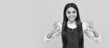 Okul üniformalı mutlu kız gülümsemesi çift tamam işaret ediyor sarı arka plan, tamam. Çocuk yüzü, yatay poster, izole edilmiş genç kız portresi, fotokopi alanı olan pankart