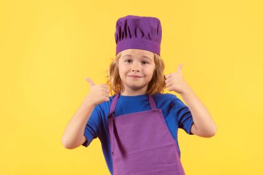 Komik çocuk şef stüdyo portresi yapıyor. Şef çocuk sağlıklı yemek hazırlıyor. Şef şapkalı çocuk portresi