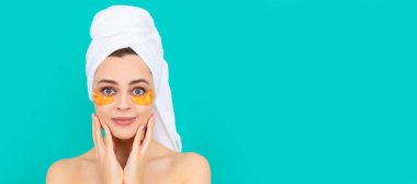 Genç kadının yüzünde havluyla kolajen altın göz bantları var. Güzel kadın, izole edilmiş yüz portresi, taklit alanı olan pankart.