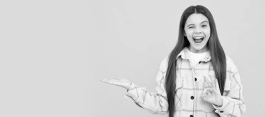 Göz kırpan mutlu genç kız pembe kareli gömlek giyer ürün sunar, fotokopi alanı, ürün teklifi. Çocuk yüzü, yatay poster, izole edilmiş genç kız portresi, fotokopi alanı olan pankart