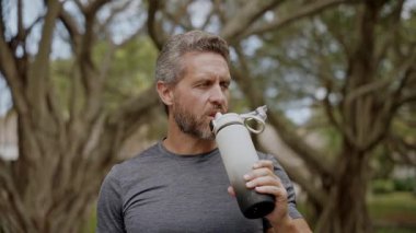 Sporcu adam susamış su içiyor. Sıvı yeterliliği. Taze bir yudum. Antrenmandan sonra susamış koşucu. Susamış adam su içiyor. Sporcu adam susamış. Sağlıklı bir yaşam tarzı. Vücuttaki su dengesi.