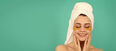 Genç bayanın yüzünde havluyla kolajen altın göz bandı olmasına sevindim. Güzel kadın, izole edilmiş yüz portresi, taklit alanı olan pankart.