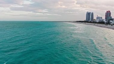 Miami plajı. Plajın tadını çıkarıyorum. Yaz tatili. Yazın deniz kenarında tatil. Deniz dalgaları. Denize açılın, rahatlayın. Turkuaz suyla havadan kumlu kumsal. Lüks tatil köyü. Rıhtıma bakan eğlence bölgesi.