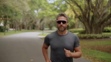 Sporcu adam koşusu. Koşucu uzun spor koşusunda. Sporcu koşucu dışarıda koşuyor. Spor koşusu. Güneş gözlüğü takan kaslı bir adam koşuyor. Sporcu koşucu. Sporcu adam egzersiz için koşuyor..