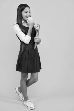 Tam boy okul çocuğu, okul çantalı genç kız izole edilmiş sarı stüdyo arka planında bir apolet tutuyor. Çocuk okulu ve eğitim konsepti