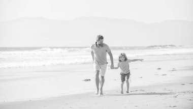 Baba ve çocuk yaz günü. Baba ve çocuk dışarıda eğleniyorlar. Çocukluk ve ebeveynlik. olumlu baba ve oğul yaz plajında koşuyorlar. Aile seyahati ve tatil. babalar ya da aile günü