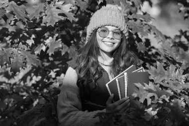 Mutlu çocuk, güz yaprakları üzerine çalışma kitabı tutuyor. Okula geri dön..