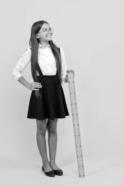 Matematik dersinde gülümseyen çocuk. Boyutunu ölçün. Trigonometri kırtasiyesi. Ölçme ve ölçme. Çocuk eğitimi. Tam boy. Genç kız cetveli tutuyor. Okula dönüyorum. Cebir ve geometri.