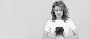 Sarı arka planda hediye kutusu olan pozitif kız, alışveriş. İzole edilmiş yüz portresi, kopyalama alanı olan pankart