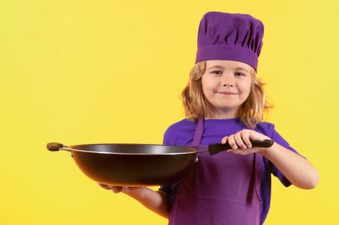Çocuk tencereyle yemek pişiriyor. Heyecanlı aşçı şefi. Çocuk fırın üniforması ve aşçı şapkası giyiyor yemek hazırlıyor, stüdyo fotoğrafı çekiyor.