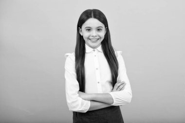 Portrait of young teenage girl standing with crossed arms against blue background with copy space