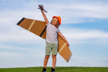 Happy childhood. Summer portrait of happy cute child. Enjoying life and nature. Little child boy is playing and dreaming of flying. Childhood concept. Little cute boy playing with a toy plane wings