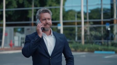 İş adamı akıllı telefondan konuşur. İş adamının telefon görüşmesi var. Olgun iş adamı telefonu kullanır. İş görüşmesi. Lider işadamı telefonda konuşuyor. Pazarlıkta iş başarısı.