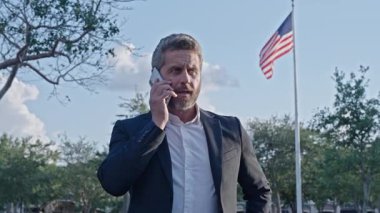 Kızgın işadamı telefonda konuşuyor. Öfke ifadesi. İş adamının telefonu var. İş iletişimi açık havada. İş görüşmesi çağrısı. Patrona telefon var. İletişim ve müzakere.