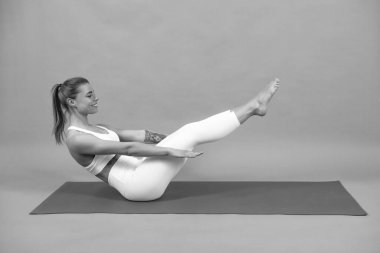 Altılı karın kası eğitimi. Fitness kadını. Spor giyimli güzel bir kız bacak egzersizi yapıyor. Spor giysileri, spor kıyafetleri. Gri arka plan yakınlarındaki eğitimde genç ve güzel bir model.