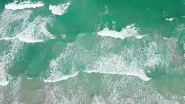 Denizde dalgalar. Dalgalar dolusu su. Okyanus girdapları. Turkuaz suyu olan havadan kumsal. Okyanus kıyısında. Deniz kıyısına dalga geliyor. Su dalgasında muhteşem bir hava manzarası. 4k görüntü.
