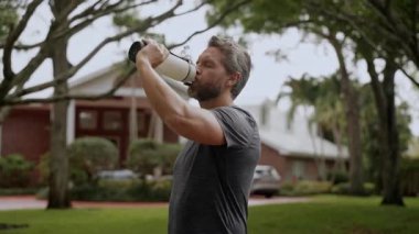 Antrenmandan sonra susamış koşucu. Susamış adam su içiyor. Sporcu adam susamış. Sağlıklı bir yaşam tarzı. Vücutta su dengesi. Sporcu adam susamış su içiyor. Sıvı yeterliliği. Yavaş çekim.