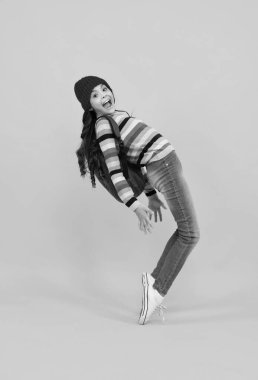 Funny school girl child student with backpack and warn hat, isolated yellow background. Learning and knowledge education concept. Autumn school. Happy teenager, positive and smiling