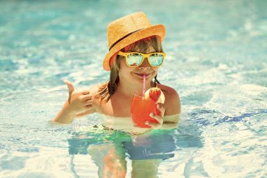 Denizdeki çocuk bir kokteyl içer. Yüzme havuzunda bir çocuk. Aktif sağlıklı yaşam tarzı, çocukla yaz tatilinde yüzme sporu aktivitesi. Çocuk kokteyli