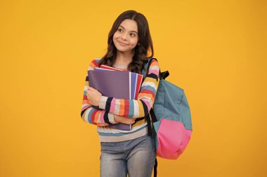 Okula dönelim. Liseli kız, sarı izole stüdyo geçmişi üzerine kitap tutuyor. Okul ve eğitim kavramı. Okul üniformalı ergen kız. Mutlu ergen, pozitif ve gülümseyen liseli