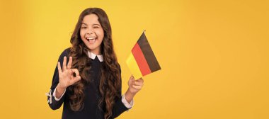 Mutlu göz kırpan çocuk Alman bayrağı sarısı arka planda iyi niyet göstergesi, yurtdışında eğitim gösteriyor. Ayrı çocuk yüzünün yatay posteri, afiş başlığı, kopyalama alanı