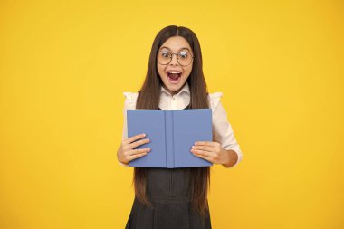 Kopya kitabı olan liseli kız izole edilmiş arka planda poz veriyor. Edebiyat dersi, ilkokul. Entelektüel çocuk okuyucusu. Heyecanlı bir yüz, neşeli genç bir kız.