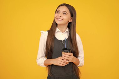 12, 13, 14 yaşlarında çocuk elinde bir fincan kapuçino ya da çay ile. Sarı arka planda servis kupası olan çocuk, sabah içeceği.