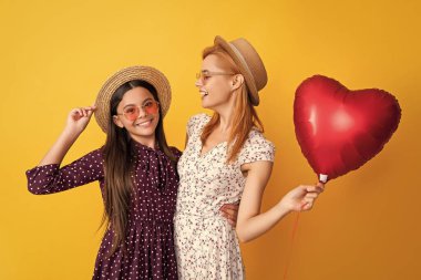pozitif anne-kız aşk balonunu sarı arka planda tutuyorlar..