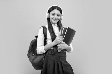 Liseli kız, 12, 13, 14 yaşlarında kulaklık takıyor ve izole stüdyo geçmişiyle ilgili kitaplar okuyor. Sırt çantalı okul çocukları