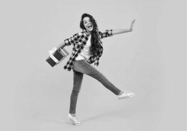 Amazed teenager. Child with gift present box on isolated studio background. Gifting for kids birthday. Excited teen girl