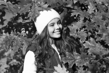 Child girl in autumn fall park outdoor, kids fun face. cheerful girl in hat at autumn leaves on natural background.