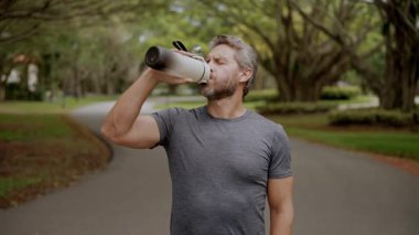 Susamış adam su içiyor. Sporcu adam susamış. Sağlıklı bir yaşam tarzı. Vücutta su dengesi. Sporcu adam susamış su içiyor. Sıvı yeterliliği. Susuz kalma. Çalışmadan sonra susamış koşucu.