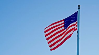 Ulusal bayrak sallayarak mavi gökyüzünde Birleşik Devletler. Bağımsızlık Günü. Vatanseverlik sembolü. Gaziler için Amerikan Bayrağı Günü ya da 4 Temmuz. Rüzgarda dalgalanan Amerikan bayrağı. ABD bayrağı..