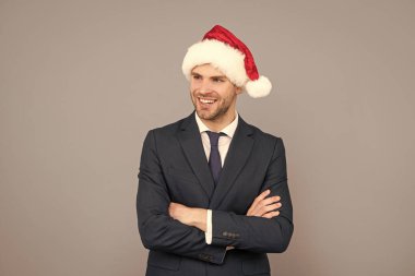 Takım elbiseli iş adamı ve Noel Baba şapkası. Xmas şirket partisi. Gri arka planda mutlu bir iş adamı. Mutlu yıllar. Mutlu Noeller..
