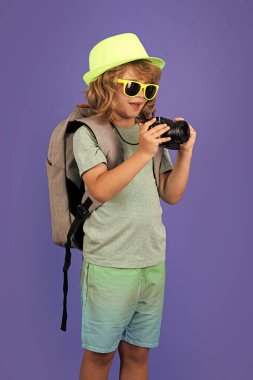Kameralı çocuk gezgin fotoğrafçı stüdyoda fotoğraf çekiyor. Çocuk fotoğraf makinesi. Yaşam tarzı seyahat kavramı