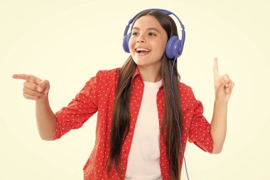 Teenager in modern wireless headphones enjoying song music in audio app, listening to her favorite music over white studio background. Happy teenager girl casual wear