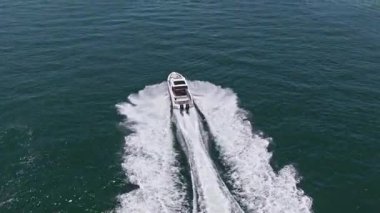 Lüks bir yaşam tarzı. Yaz tatili. Denizde yat. Derin mavi denizde yelken açan sürat teknesi. Motorlu teknenin üst görüntüsü. Denizde lüks tekne motorlu yatı. Tekne turizmi..