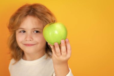 Stüdyoda elmalı çocuk. Stüdyo portresi sarı arka planda elma tutan şirin bir çocuk.