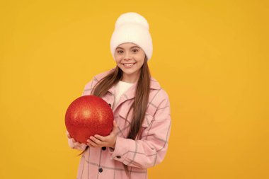 Kış şapkalı neşeli çocuk sarı arka planda Noel süslemesi balosu düzenliyor..