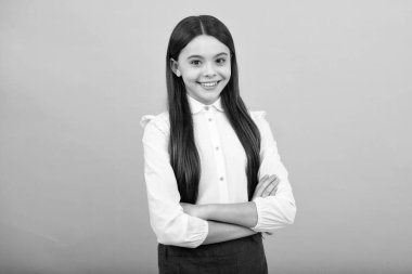 Mavi arka planda kollarını kavuşturmuş genç bir kızın portresi. Çocuk yaşam tarzı konsepti