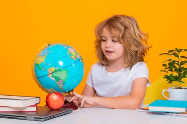 Nerd pupil boy from elementary school with book isolated on yellow studio background. Smart genius intelligence kid ready to learn. Back to school