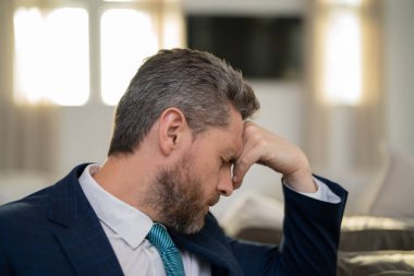 Baş ağrısı, yorgunluk ve stres. Takım elbiseli bir iş adamı dizüstü bilgisayar kullanıyor, migreni tuttu. Baş ağrısı konsepti. Ofiste acılı adamlar streslidir. Stresli ve baş ağrısı