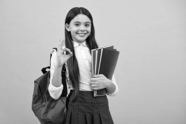 Okul çantalı genç kız mavi izole stüdyo geçmişi üzerine kitap tutuyor. Çocuk okulu ve eğitim konsepti