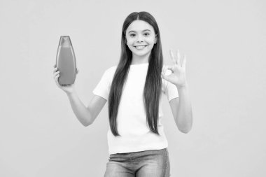 Şampuan kremi kullanan bir çocuk. Günlük kozmetik bakım. Gençlerin elinde saç ve cilt bakımı şişesi var. Güzellik sağlığı ve kozmetik ürünleri. Mutlu ergen portresi. Gülümseyen kız