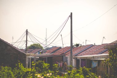 Photo of row of houses with roof tile and power pole element located in Indonesia. Roof tile of house photo photo on a sunny day clipart