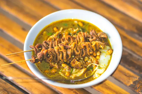 stock image Chicken porridge bowl served with unique dishes. Traditional chicken porridge with chicken intestine satay dishes, authentic traditional from Indonesia. Macro photo of traditional food from Indonesia.