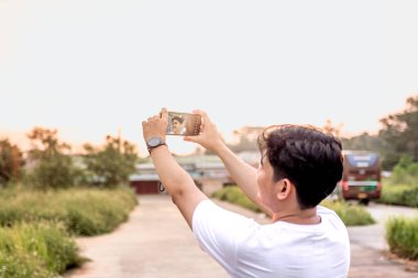 a man who is taking photos of himself and nature in various styles. the man has his back to the camera. set on a sunny afternoon in nature.a man who is taking photos of himself and nature in various styles. the man has his back to the camera. set on  clipart