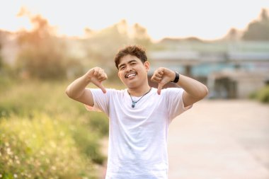 Başparmağı aşağıda duran bir adam. Adam sanki birisi bir şeyi küçümsüyormuş gibi davrandı. Güneşli bir öğleden sonra doğada geçiyor..