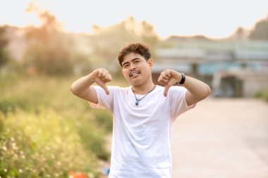 Başparmağı aşağıda duran bir adam. Adam sanki birisi bir şeyi küçümsüyormuş gibi davrandı. Güneşli bir öğleden sonra doğada geçiyor..